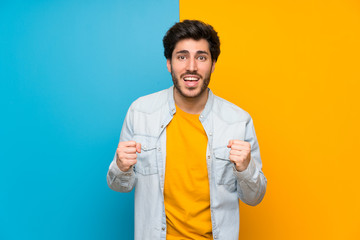 Handsome over isolated colorful background celebrating a victory in winner position