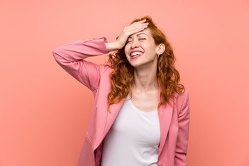 Naklejka premium Redhead woman in suit over isolated pink wall laughing