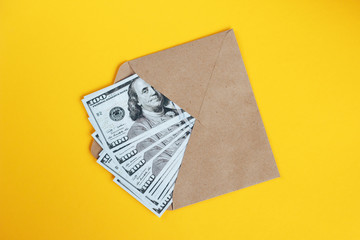 Paper envelope with money on a yellow background.