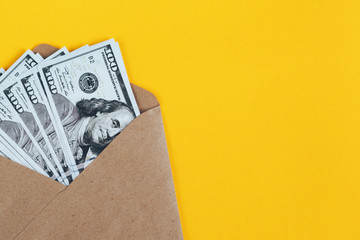 Paper envelope with money on a yellow background.