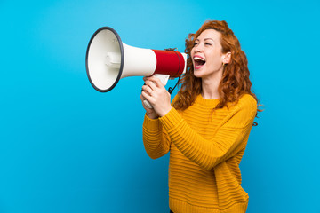 Redhead woman with yellow sweater shouting through a megaphone - obrazy, fototapety, plakaty