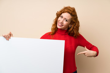 Redhead woman with turtleneck sweater holding an empty white placard for insert a concept