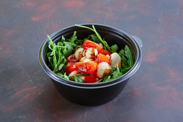 Salad with mozzarella, tomato and arugula in take away packaging