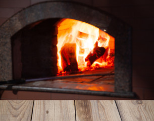 fire in old brick oven on wooden table background