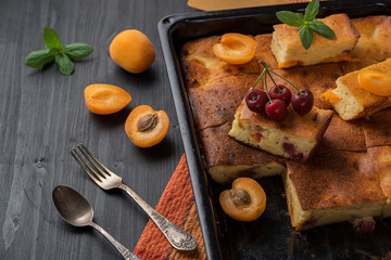 Fruit tart and apricots on a black wooden table.