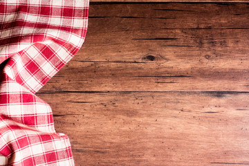 Checkered red napkin on an old wooden brown background, top view. Image with copy space. Kitchen table with a towel - top view with copy space. 