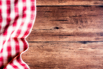 Checkered red napkin on an old wooden brown background, top view. Image with copy space. Kitchen table with a towel - top view with copy space. 