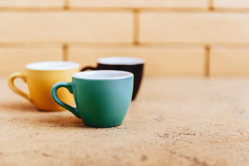 Three color coffee cups on light background copy space
