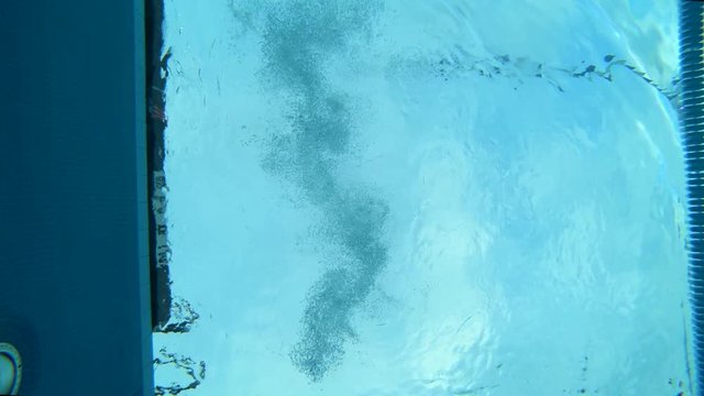 Underwater shot of a woman diving into a lap pool wearing professional swimwear.