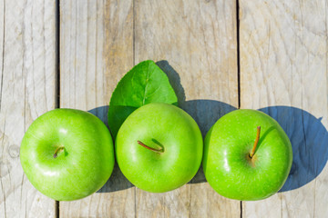 Freshly cropped geen apples on wooden table, top view