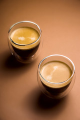 Black coffee with froth in modern cups on a plain background