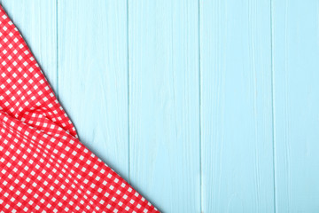 Checkered picnic blanket on wooden background, top view. Space for text