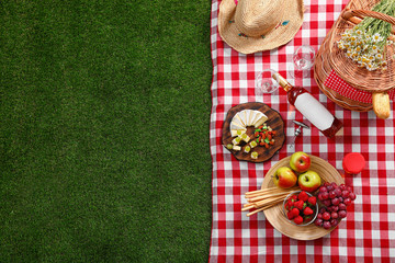 Flat lay composition with picnic basket and products on checkered blanket outdoor, space for text