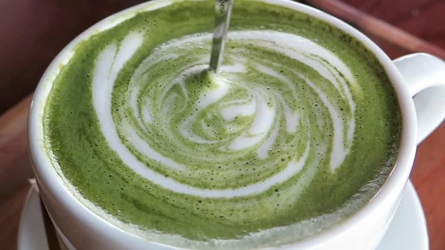Slow reverse motion on green matcha latte with spoon diving in foam