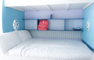 Pink canvas bag on the blue shelf beside the bed
