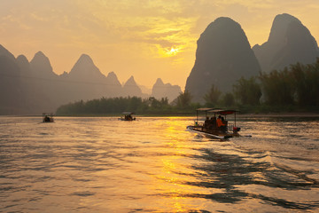 Tourists ride along the Li River (Lijiang River) on traditional bamboo rafts and admire the...