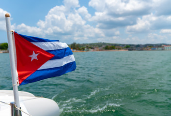 Cuba flag waving on boat at sea near Cuban coastline