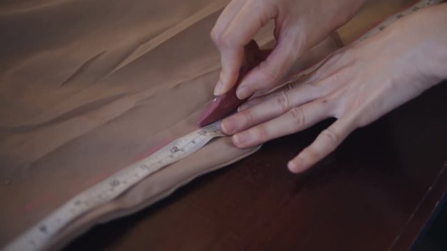 Seamstress making a pattern on beige fabric.