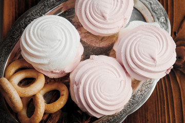 Silver plate of strawberry vanilla marshmallow and sushki on wooden background.