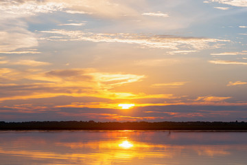 Sunset reflection lagoon. beautiful sunset behind the clouds and blue sky above the over lagoon landscape background. dramatic sky with cloud at sunset