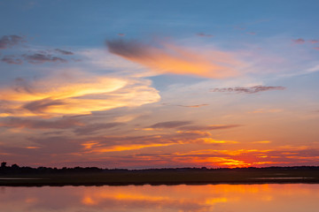 Sunset reflection lagoon. beautiful sunset behind the clouds and blue sky above the over lagoon landscape background. dramatic sky with cloud at sunset