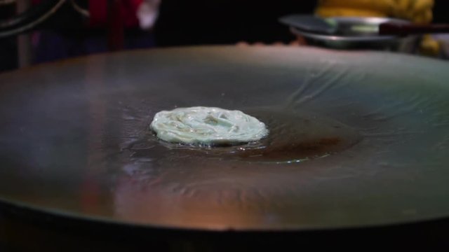 Close up of Thai roti fried on pan, slow motion