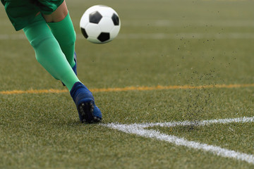 Obraz premium Foot of a child football player and ball on the football field