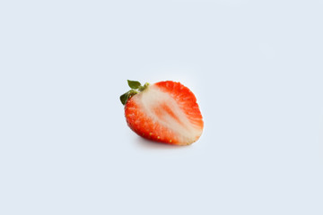 half red strawberry on light blue background close-up