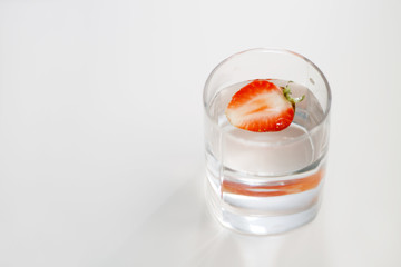 red strawberry in a glass of lemonade top view close-up on white background