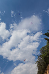 Paragliding in Spain. Man flying at parachute in the mountains. Green hills and red parachute. Cloudy day, beautiful nature