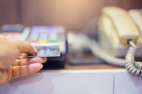 Hand put credit card In slot of credit card reader and telephone.