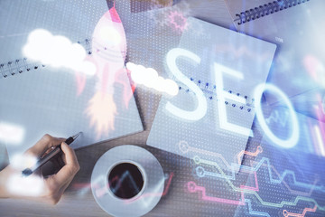 Double exposure of woman's hands making notes with SEO icon. Concept of Search engine optimization