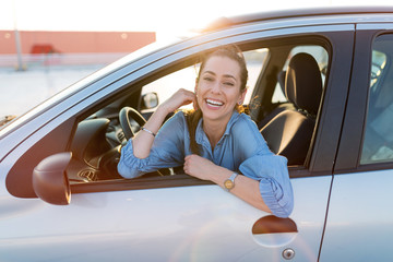 Happy woman driving a car and smiling