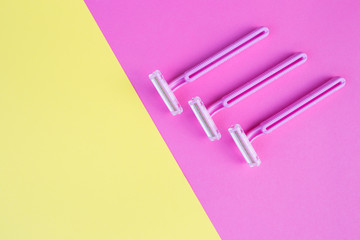Three women's razors pink on an isolated pink and yellow background.