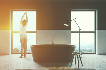 Woman in white and black bathroom with tub