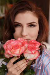 Closeup portrait of a beautiful brown-haired woman with a bouquet of roses.