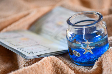 Beach themed candle and open passport with stamps, concept of travel