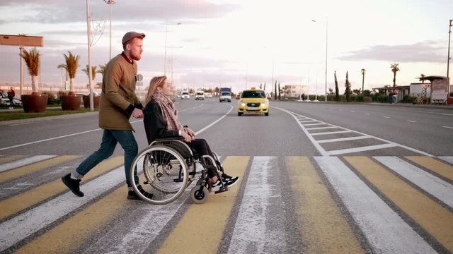 Man is removing disabled woman in carriage over pedestrian crossing in city
