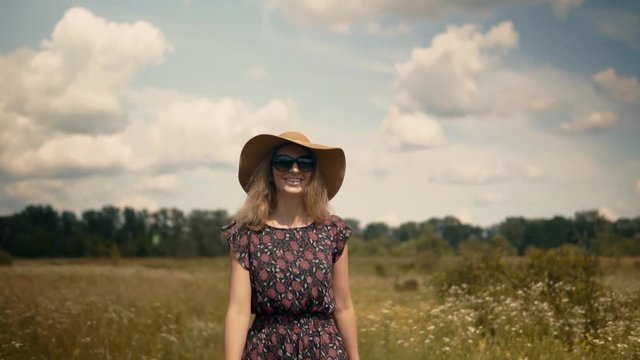 Girl Relaxing.Girl Walks Through Field. Pretty Ledy In Dress.Woman In Hat Walking On Field.Woman In Hat.Wicker Hat.Romantic Woman Walking On Field.Sexy Woman On Sunglasses.Blonde Girl On Sunglasses.