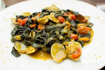 Fototapeta na wymiar Seafood pasta dish, Italian black fettuccini with vongole clams and mussels