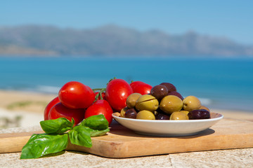 Italian appetizer green and black olives in olive oil, tomatoes and marinated artichokes close up