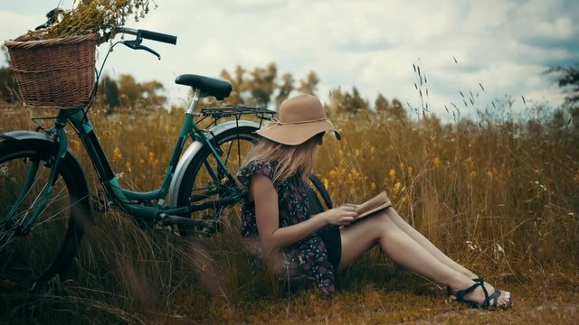 Blonde Woman Relaxing.Beautiful Woman In Dress And Hat.Attractive Girl In Hat Reading Book.Beautiful Girl Read Book.Beautiful Girl In Hat.Attractive Girl On Sunglasses.Female With Bicycle.Woman Relax.