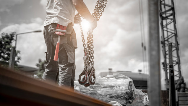 Bauarbeiter entl&auml;dt Bewehrungsstahl von LKW und h&auml;ngt die Last an die Ketten des Krans