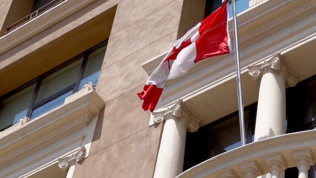Flag of Canada waving on a windy day on the consulate of Canada . Red and White, the colors of the Maple Leaf
