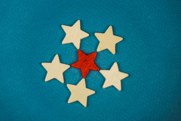 a bunch of wooden stars and one of them is highlighted in red. subject on blue background