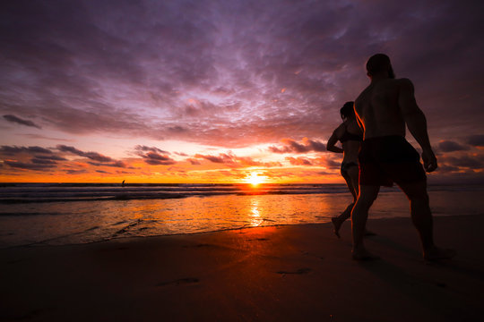 Couble walking at the beach on a purple sunset