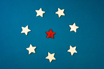 a bunch of wooden stars and one of them is highlighted in red. subject on blue background.