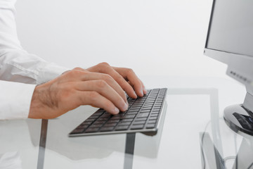 Doctor in a white medical coat typing on a black keyboard. Businessman in a white shirt is writing a text using a black keyboard.