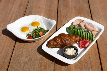 Breakfast is set. Whole grain sandwich with fried egg, vegetables and herbs on a wooden table, morning mood,