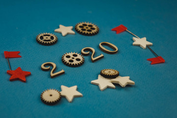 2020 number from wooden numbers on a blue background with scattered stars gears and flags around